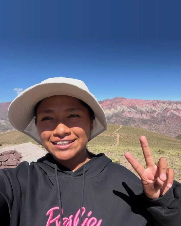 Tatiana, da Humahuaca Travel, sorrindo e fazendo o V da vitória em frente à Serranía del Hornocal